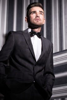 Portrait of a handsome man in a suit and a tie who is posing over a striped background